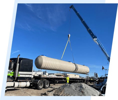 A crane is lifting a large tank on the back of a truck.