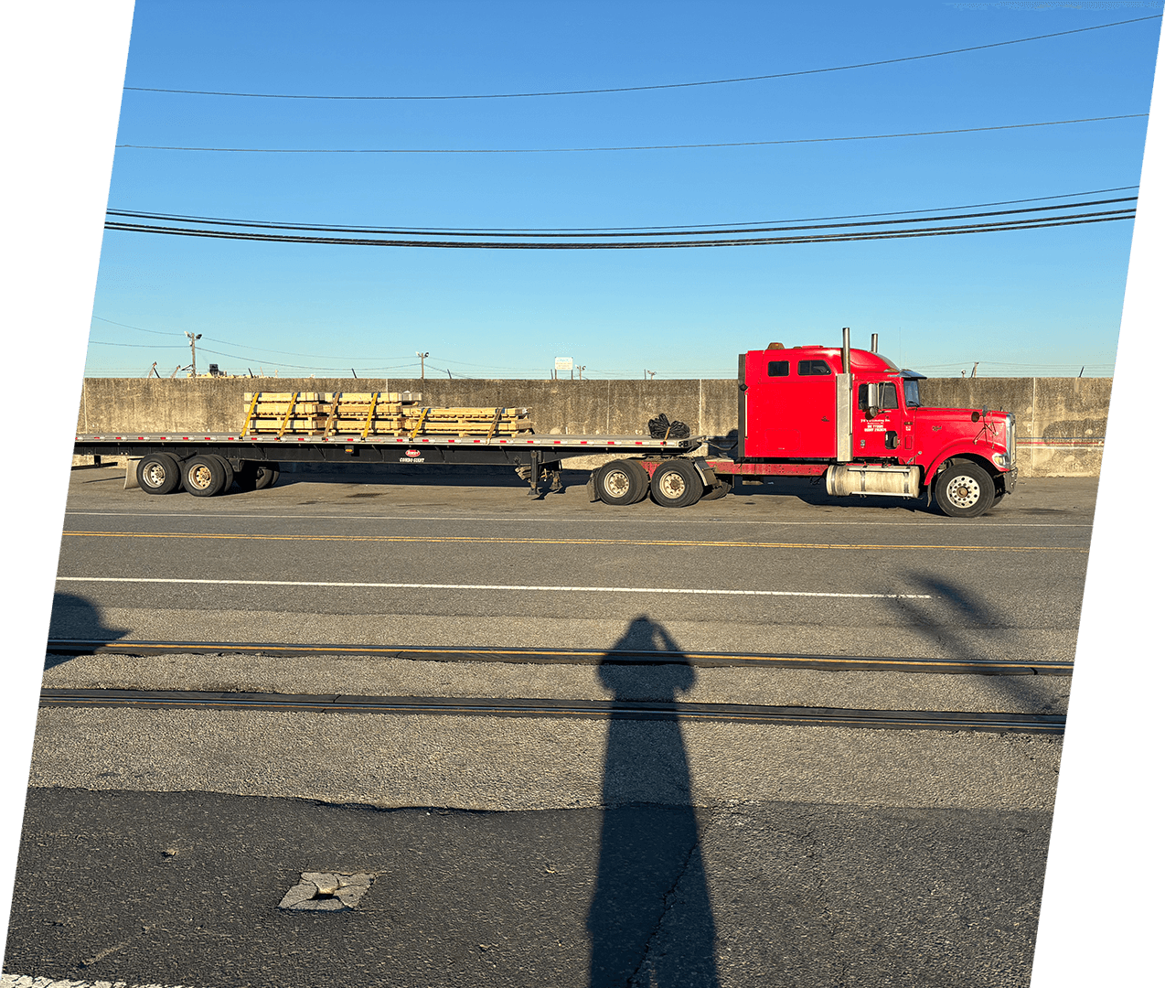 A red truck is pulling a trailer down the road.