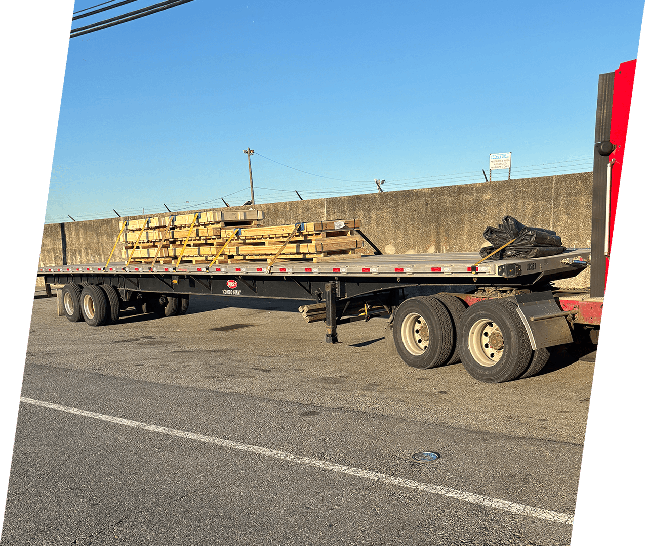 A flatbed trailer with many wooden logs on it.