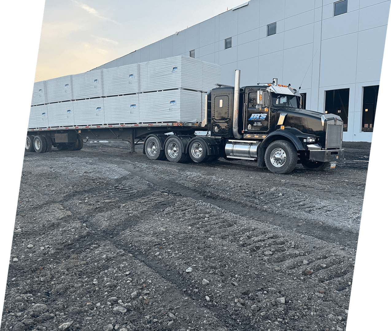 A large truck is parked in front of a building.