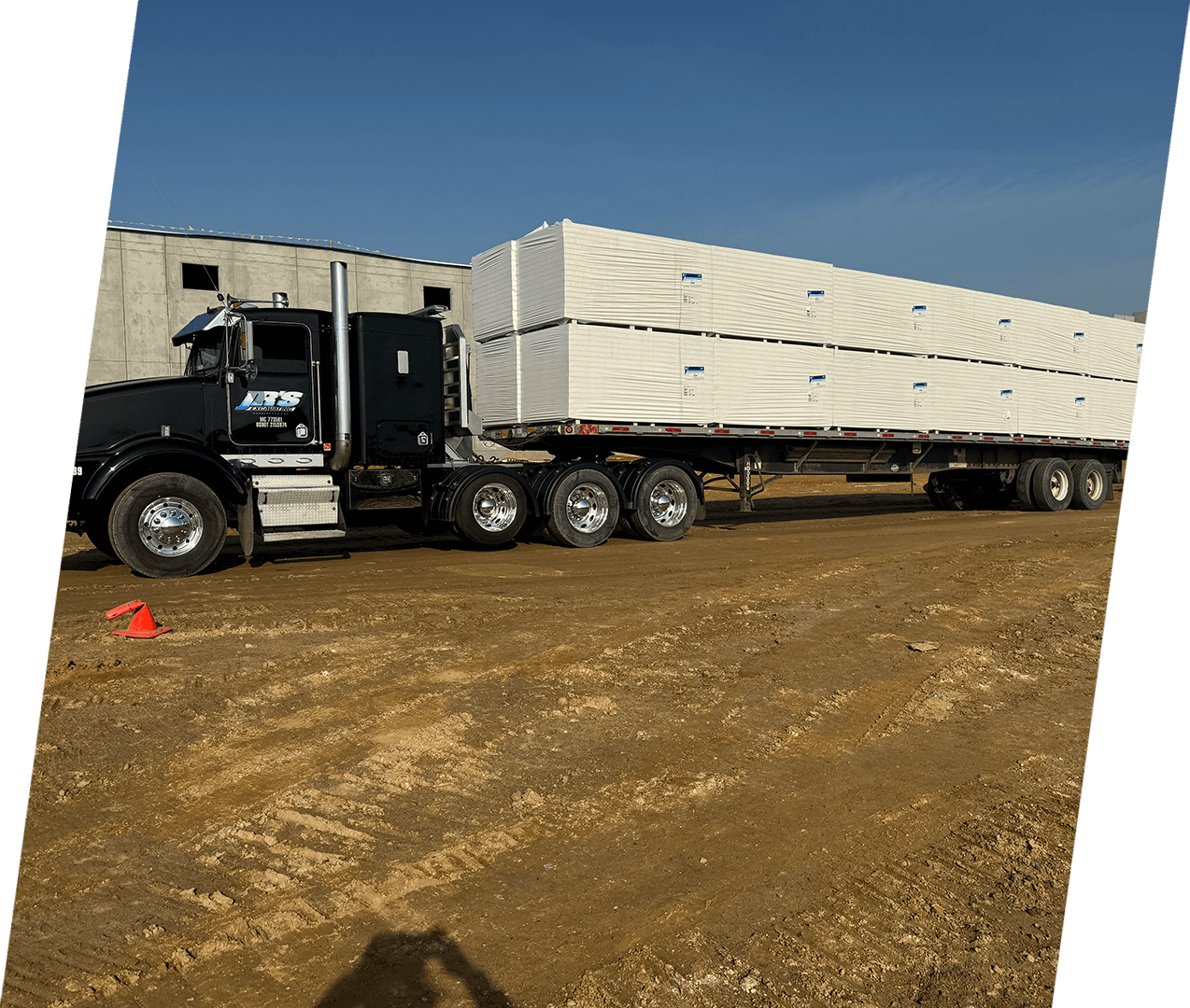 A semi truck is parked in the dirt.