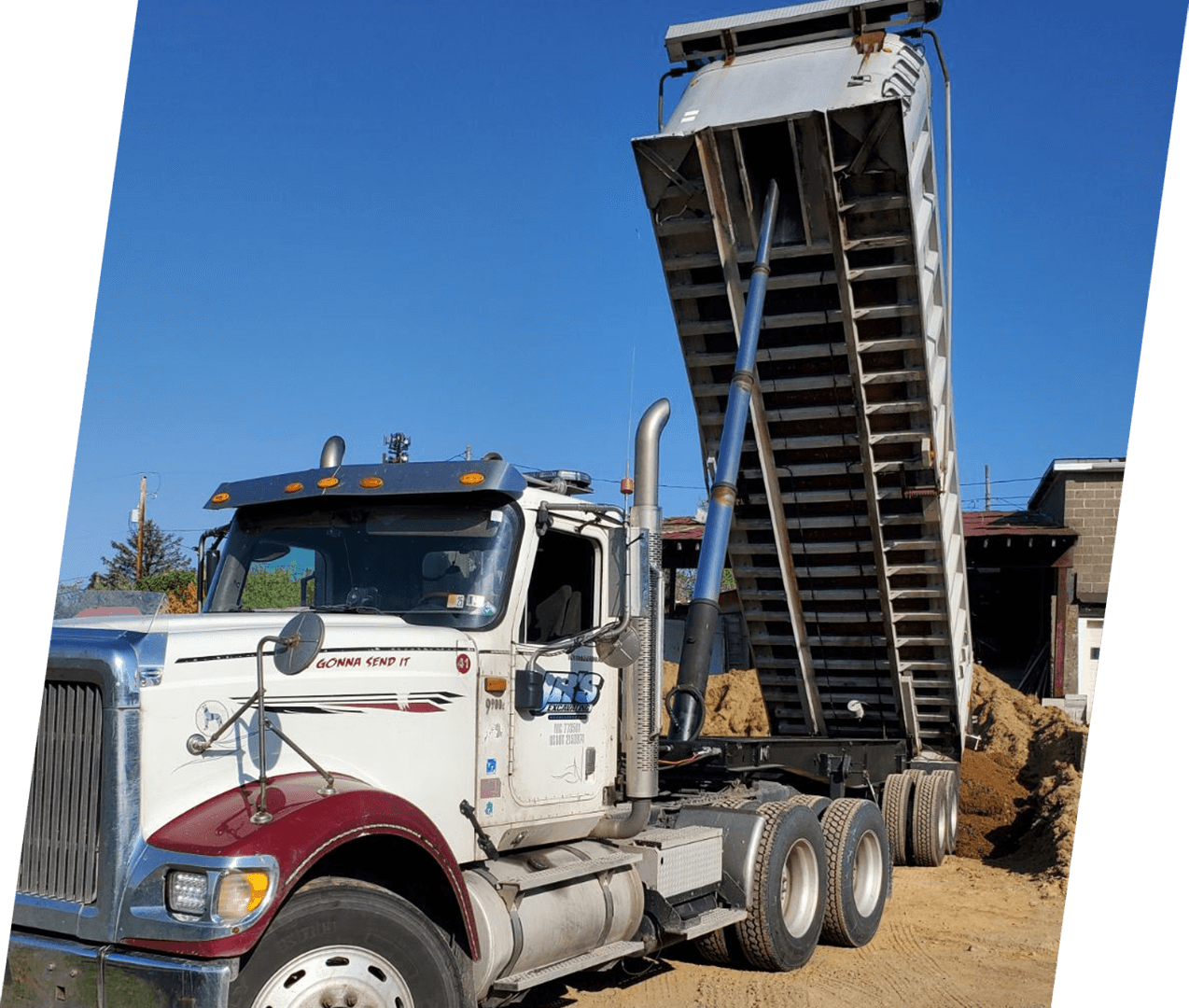 A large truck is parked in the dirt.