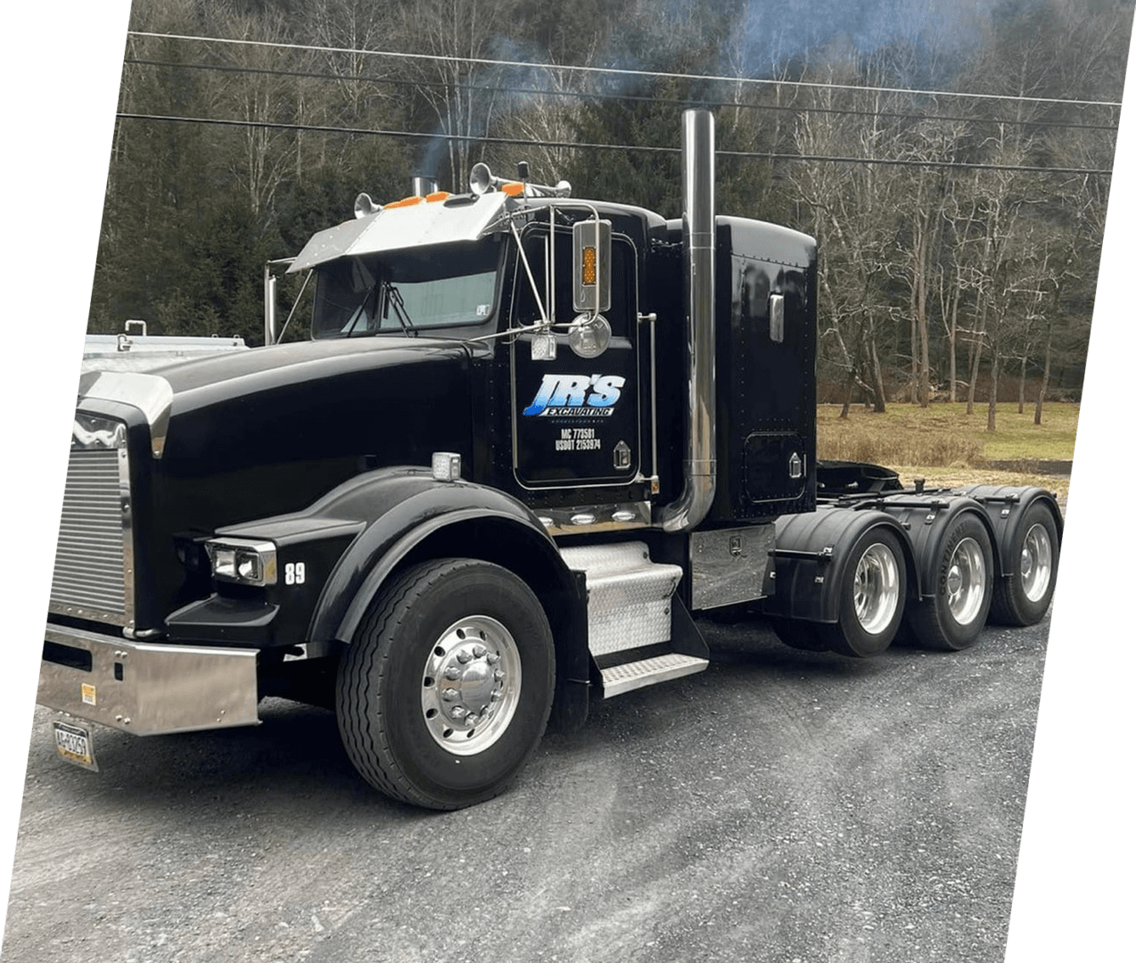 A black semi truck parked on the side of a road.