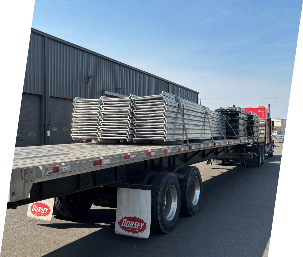 A flatbed truck with stacks of metal sheets on the back.