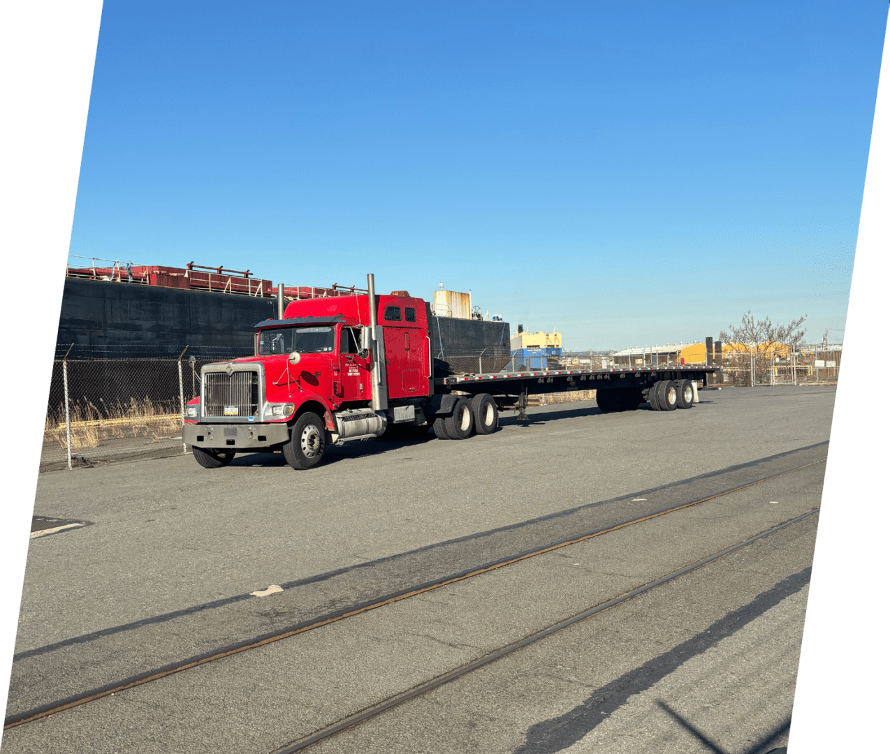 A red truck is pulling a trailer down the road.