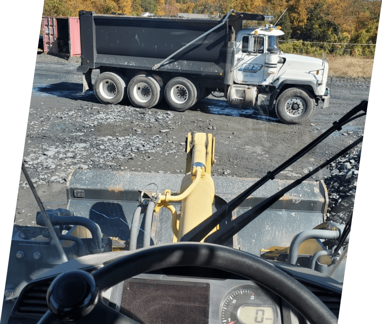 A dump truck is parked in the middle of a road.