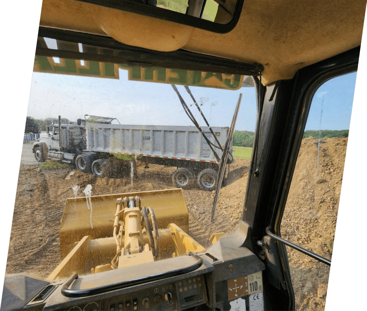 A tractor is driving down the dirt road.