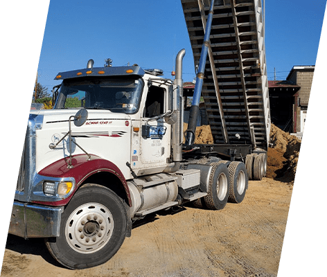 A large truck is parked in the dirt.